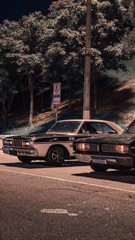 Classic vintage cars parked under streetlights at night, creating a retro vibe.