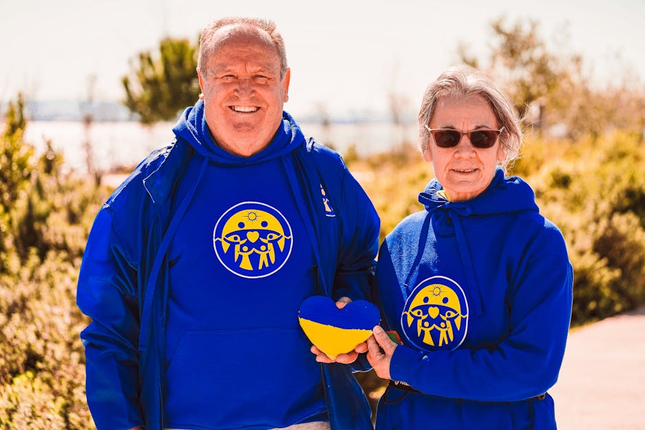 Mature couple wearing blue hoodies holding a Ukraine-themed heart, symbolizing support and care.