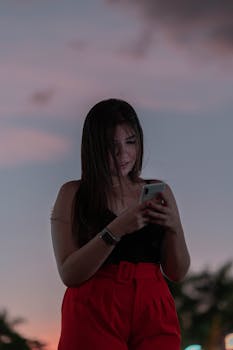 Young woman in red shorts using smartphone outdoors in twilight mood.