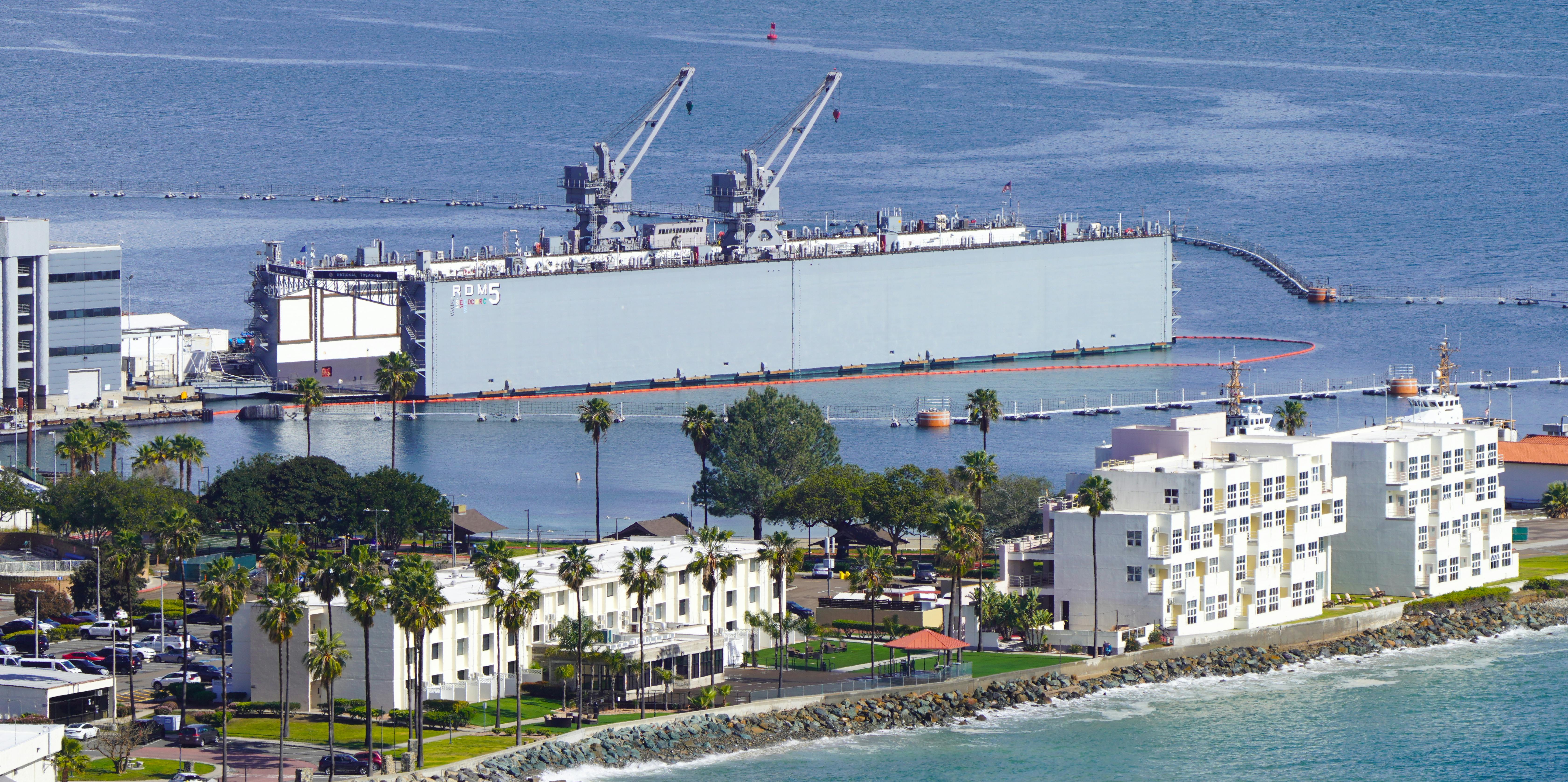 Aerial view of San Diego harbor featuring a large cargo ship and waterfront buildings.