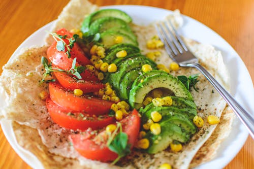 Rodajas De Tomate Y Aguacate En Un Plato Blanco