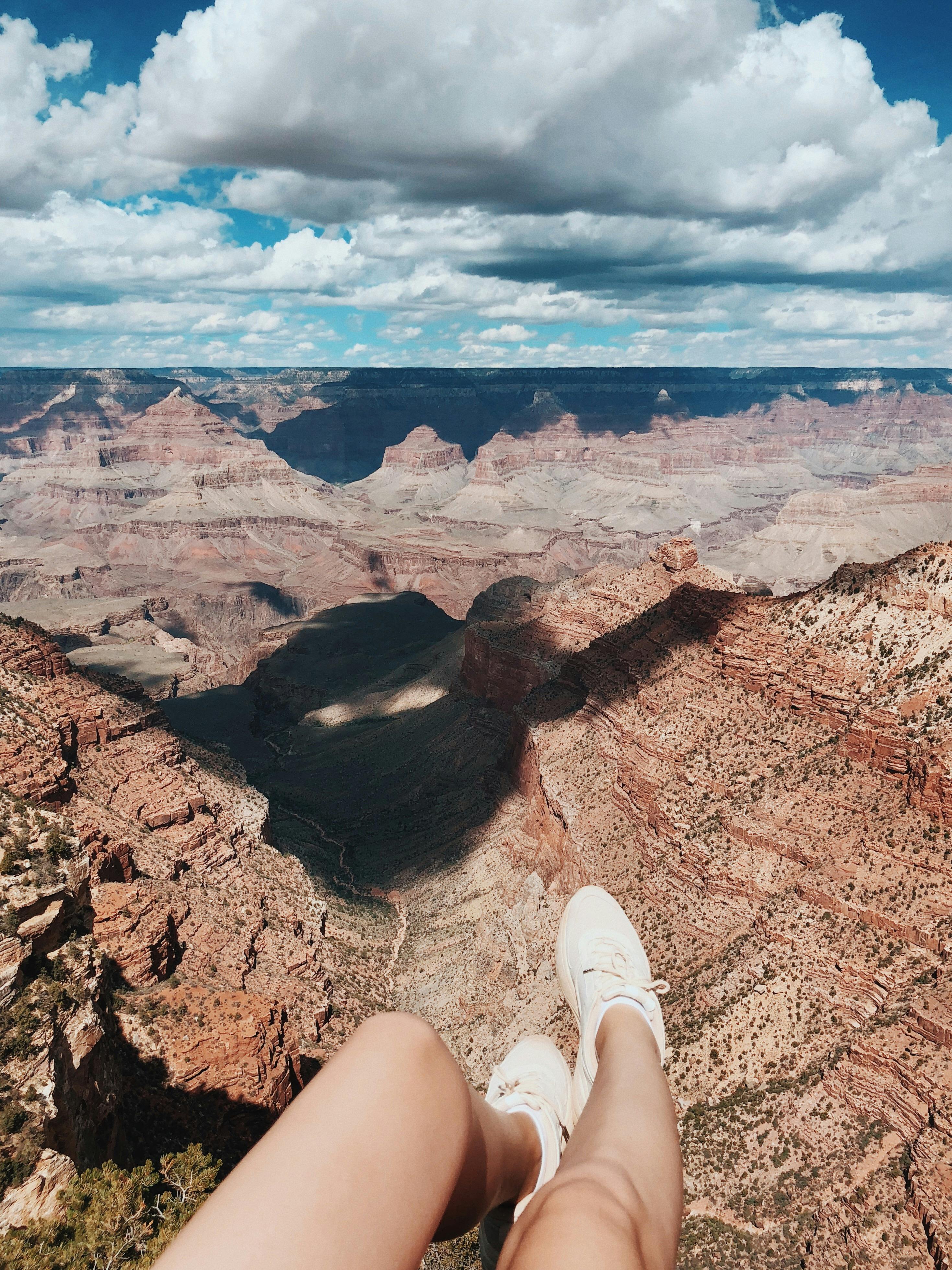 a person sitting on a cliff with a view of the grand canyon national park