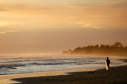 A Person Standing on the Beach During Golden Hour