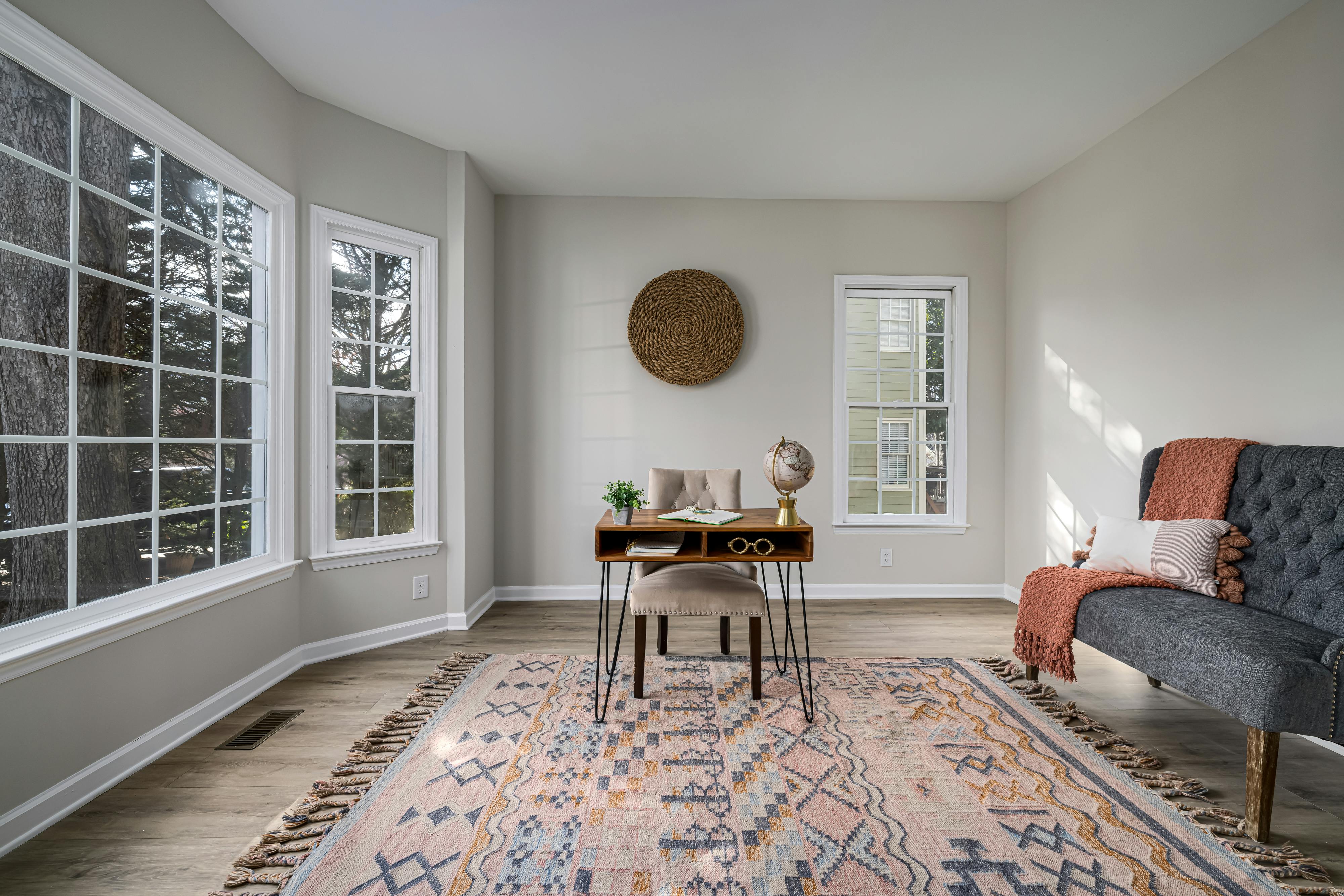 A stylishly decorated garage conversion, featuring a comfortable seating area, a desk, and large windows bringing in natural light, showcasing its versatility as a home office or guest suite. - Garage conversion plans