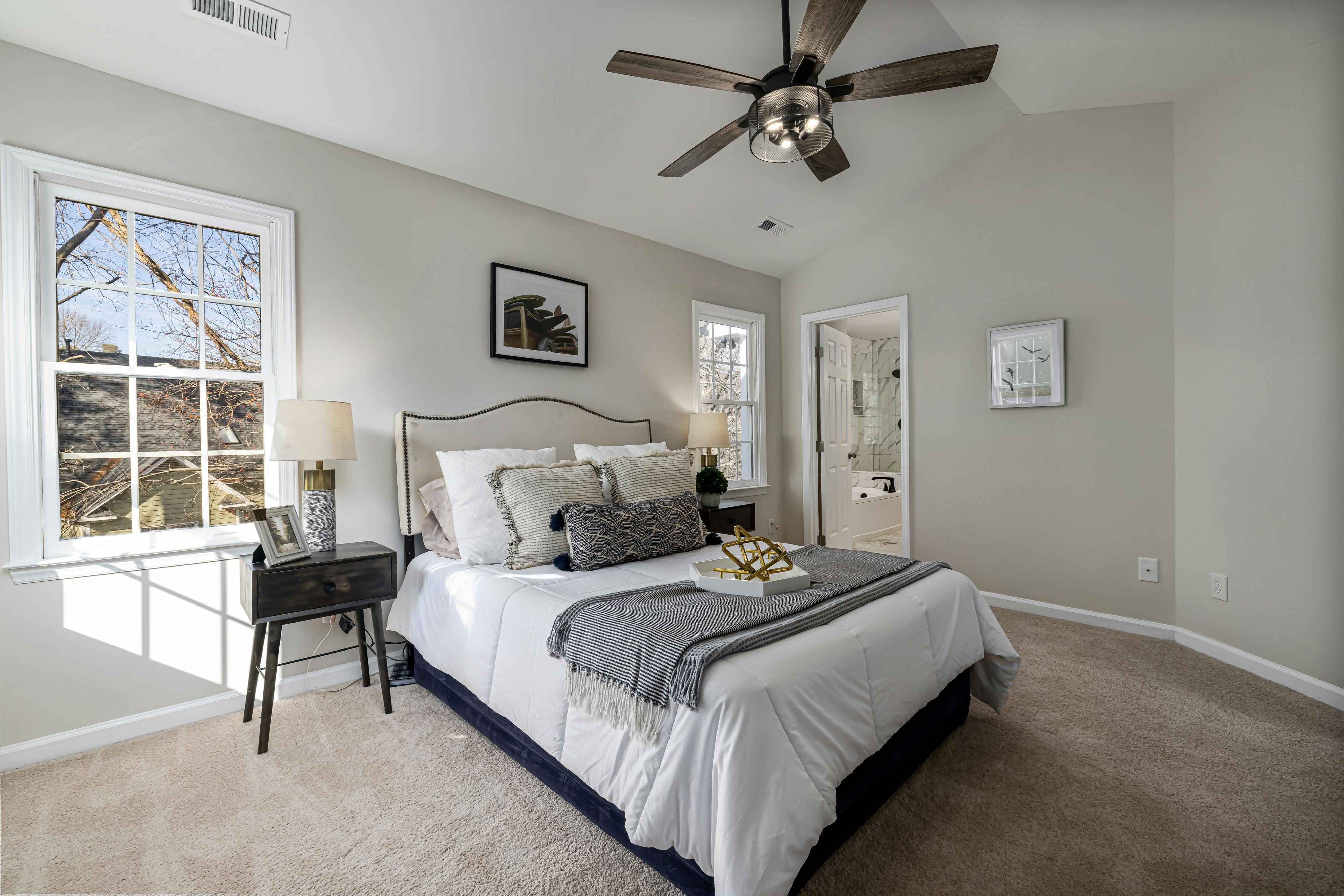 Free A bright, cozy bedroom featuring a ceiling fan, modern decor, and comfortable bedding. Stock Photo
