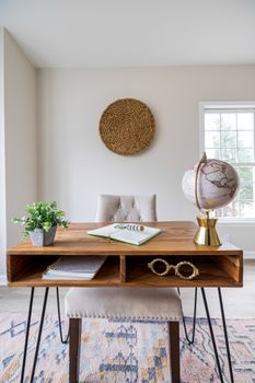 Minimalist home office featuring a wooden desk, chair, globe, and decor for elegant interior design.
