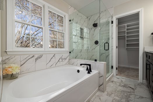 Luxurious bathroom with marble tiles, bathtub, and glass shower in elegant home interior.