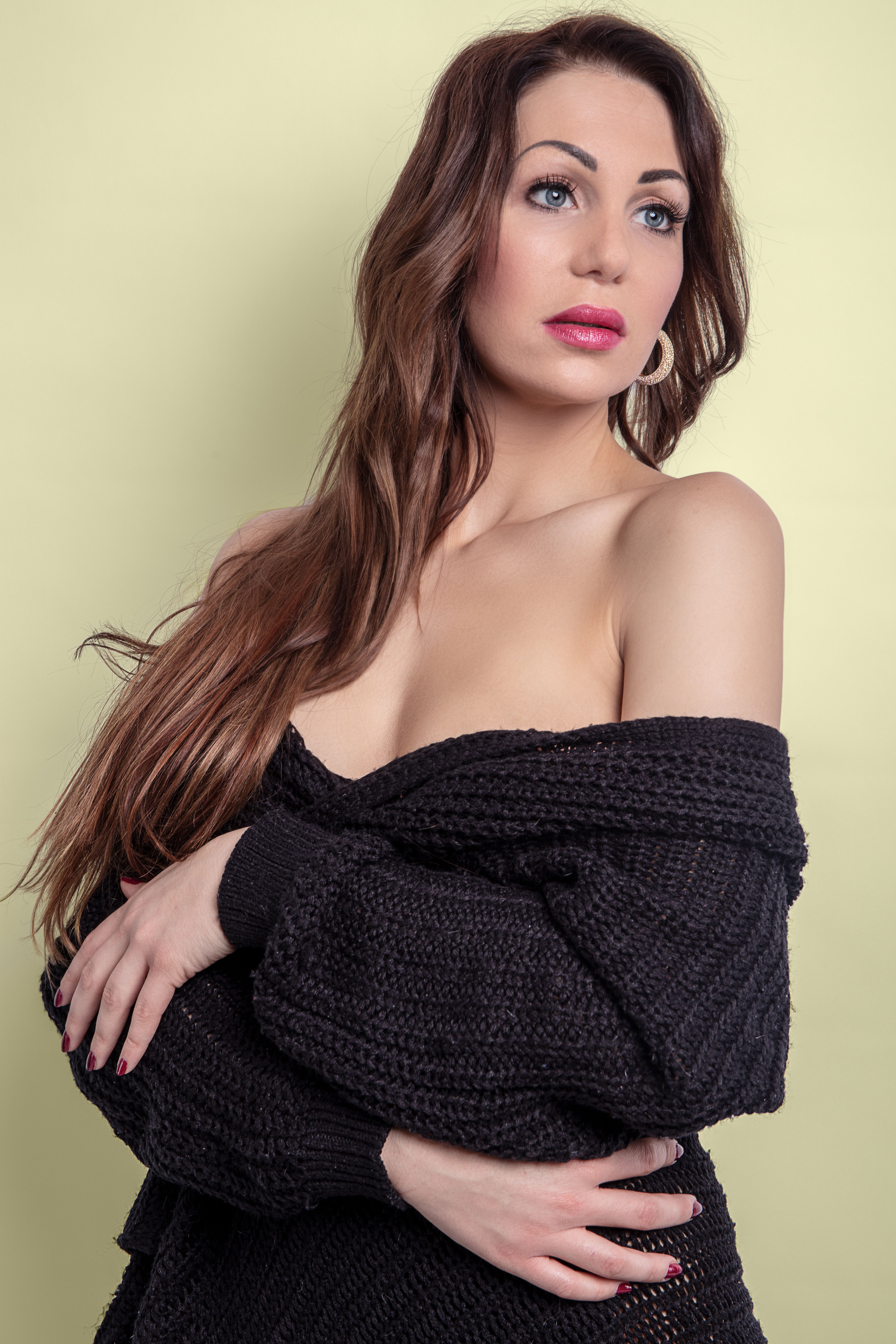 Portrait of a stylish woman in a black sweater with a light green background.