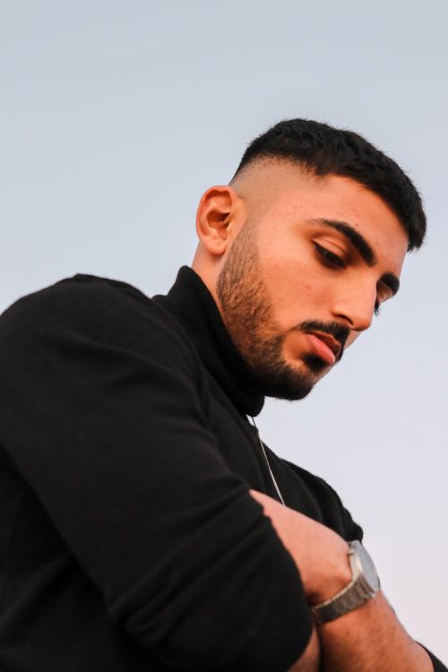 Free Close-up portrait of a young man with arms crossed, sky background. Stock Photo