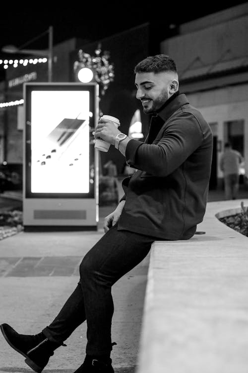 Grayscale Photo of a Man Holding a Cup of Drink