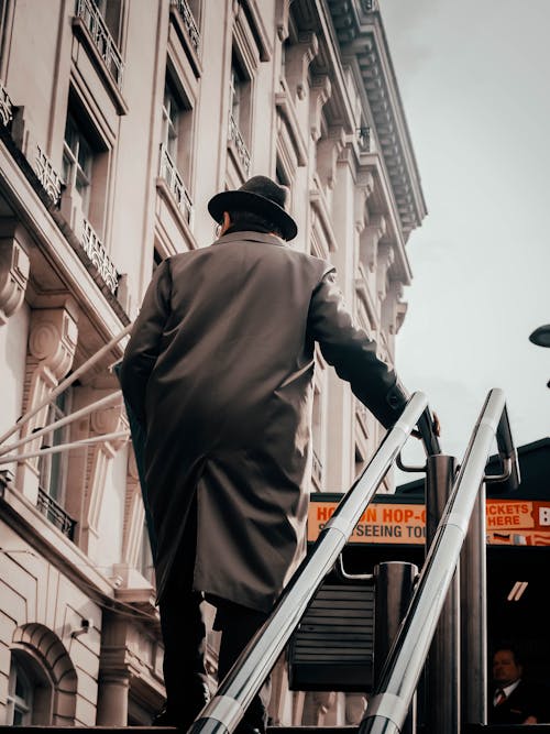 Free Man in Coat and Hat Walking up the Stairs  Stock Photo