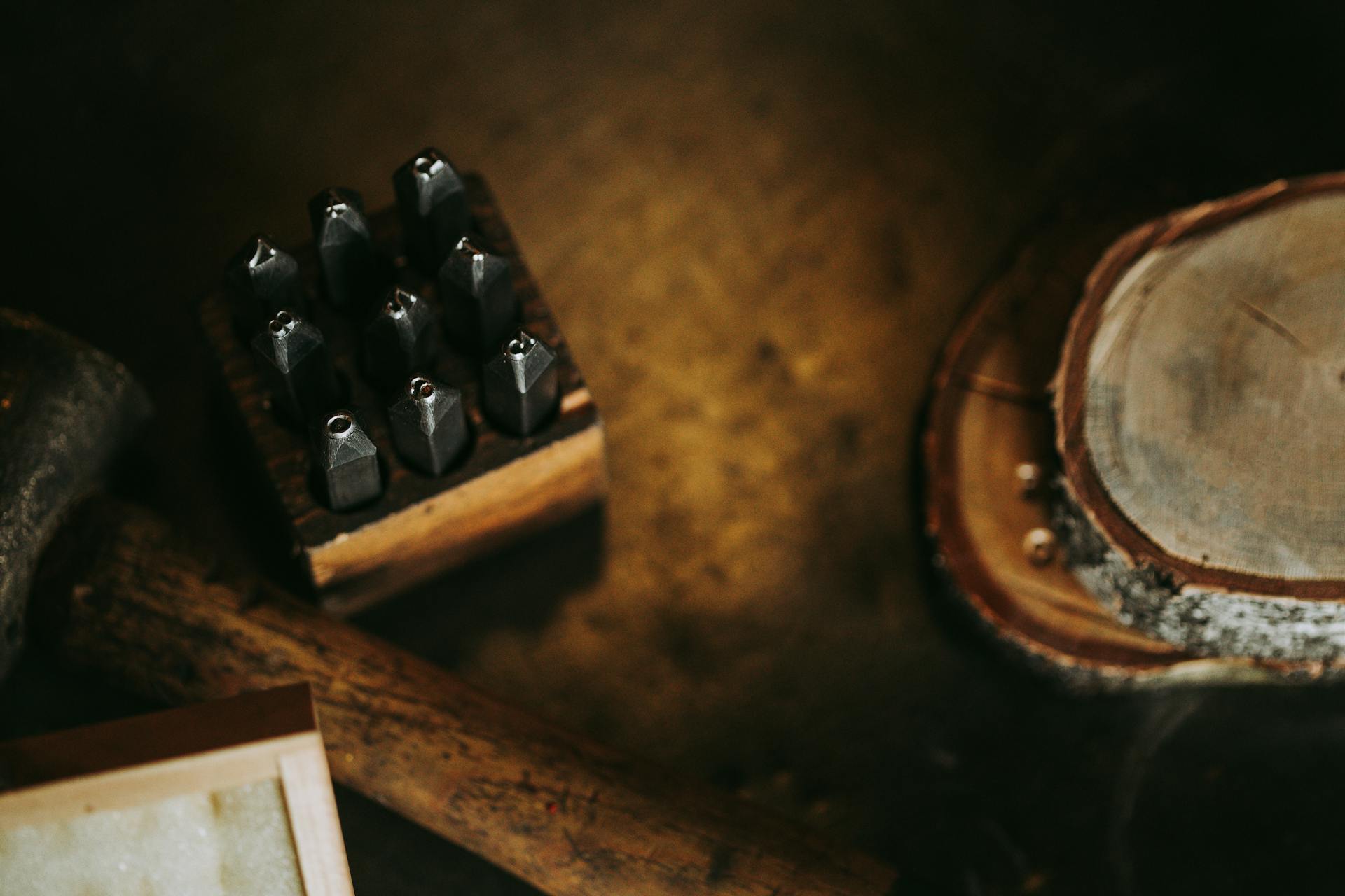 Close-up of vintage metal stamping tools on a rustic wooden table, showcasing handmade craftsmanship.