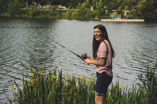 Femme En Chemise Rayée Rouge Et Short En Jean Bleu Tenant Une Canne à Pêche