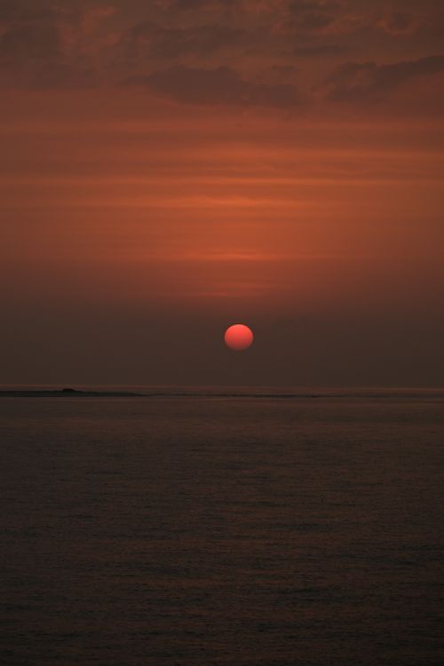 Free Tranquil sunset view with a glowing sun over calm ocean waters, creating a peaceful seascape. Stock Photo
