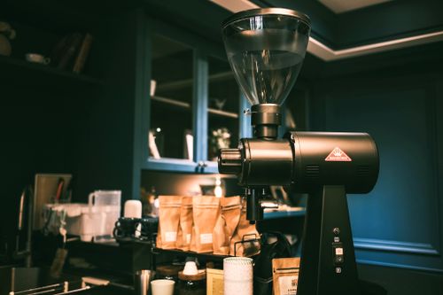 Free A sleek coffee grinder in an inviting cafe with warm lighting and packaged beans. Stock Photo