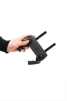 A close-up of a hand holding a drone controller against a white background, emphasizing technology.