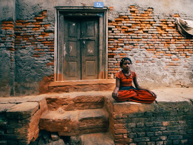 Indian Girl Sitting Near Old Brick House