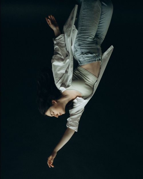 Free Striking upside down portrait of a woman on a dark background conveying artistic expression. Stock Photo