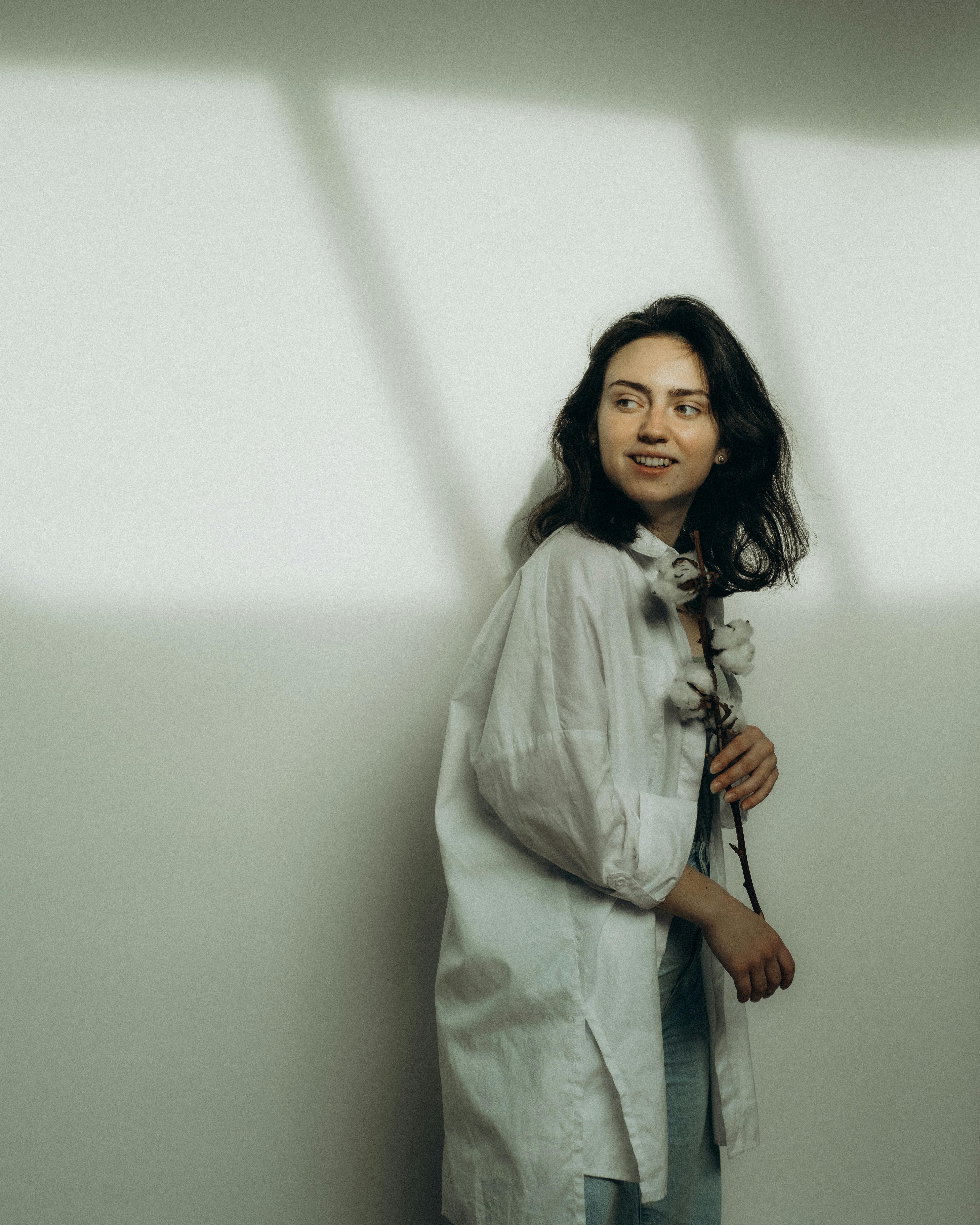 Artistic portrait of a woman in white holding dried flowers, set in London with soft lighting.