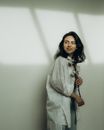 Woman in White Long Sleeve Shirt Standing Beside White Wall