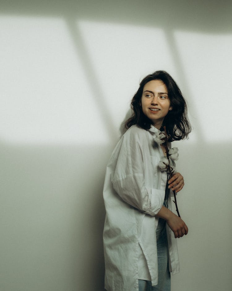 
A Woman In A White Long Sleeved Shirt Holding A Dried Cotton Flower