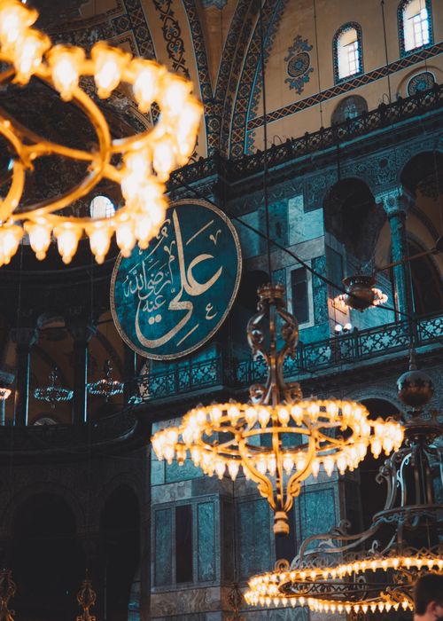 Free Elegant chandeliers illuminate the rich interior of a historic Istanbul mosque, showcasing Islamic art and architecture. Stock Photo