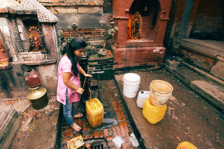 Woman Pumping Water Into Containers 