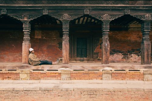 Free A man in a cap sits by ancient columns, embodying cultural heritage. Stock Photo
