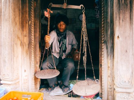A traditional merchant using vintage scales in a rustic setting. Perfect for lifestyle and cultural themes.