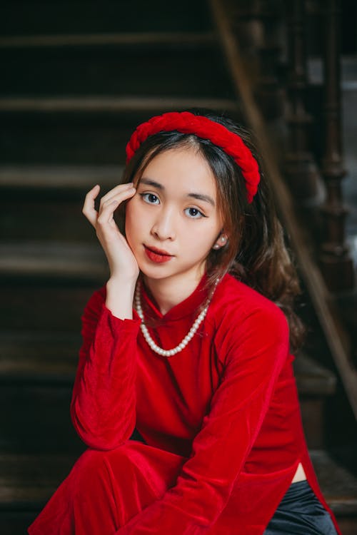 Free Girl in Red Ao Dai and Pearl Necklace Sitting on Stairs Stock Photo