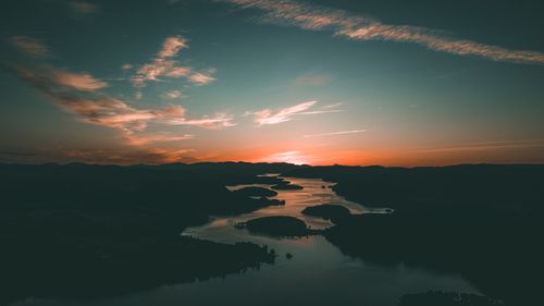 Free A stunning aerial view of a vivid sunset casting reflections on winding waterways and silhouetted landscapes. Stock Photo