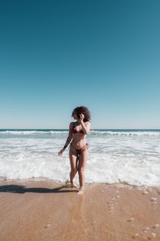 Woman in swimwear enjoying the waves at St. Augustine Beach under a blue sky.
