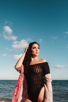 Confident woman in a swimsuit posing at Miami Beach under a clear sky.