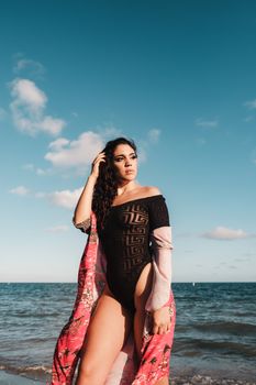 A fashionable woman posing confidently on a sunny Miami beach with a vibrant scarf.