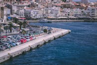 港口热闹非凡，汽车停放在岸边，建筑物充满活力，海水清澈见底