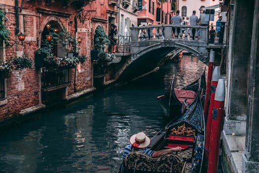 A scenic view of a gondola passing under a traditional Venetian bridge in vibrant Venice. by hitesh choudhary