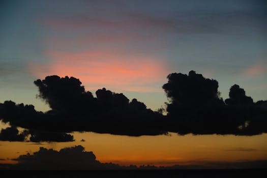 Capture of a dramatic sunset with silhouetted clouds, showcasing vibrant twilight hues.