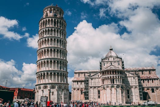 The Leaning Tower of Pisa and Cathedral with tourists and vibrant sky.