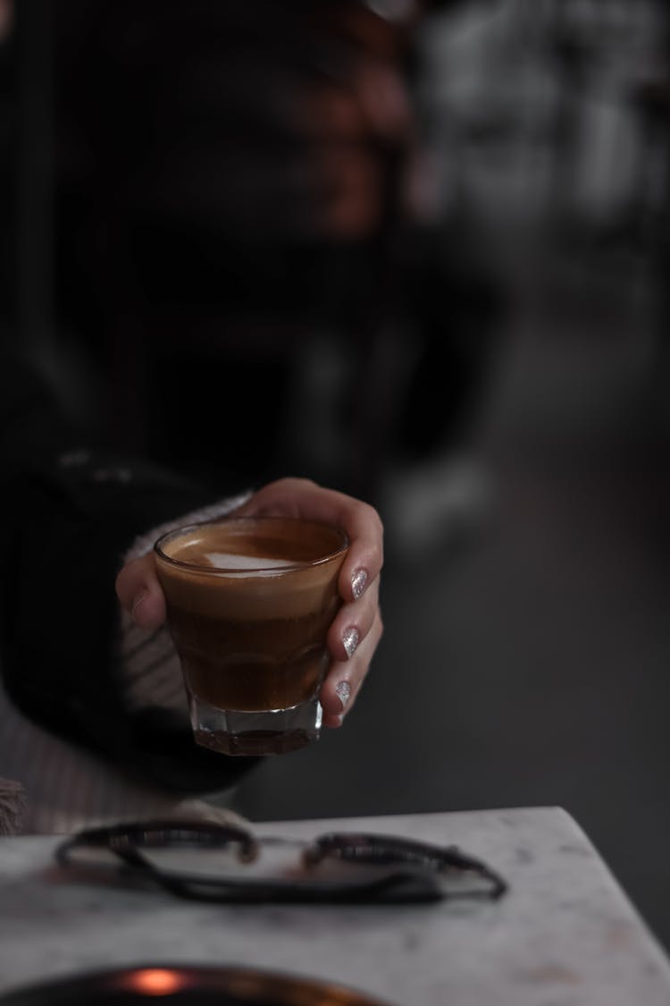 A Hand Holding A Glass Of Coffee 