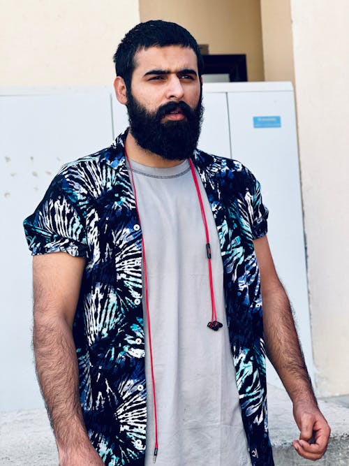 A Bearded Man in Gray Shirt Under Blue Button Down Polo Standing while Looking Afar