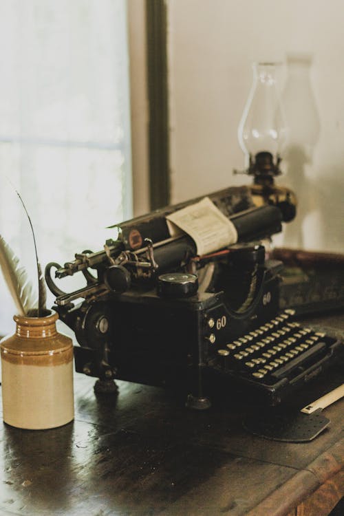 Black Vintage Typewriter Beside Quills on a Wooden Surface