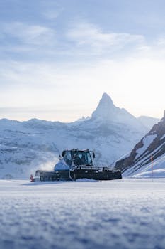 A snowplow operates on a snowy landscape with the iconic Matterhorn mountain in view.