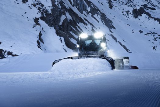Snow groomer making fresh tracks on a snowy Zermatt mountain slope during winter.