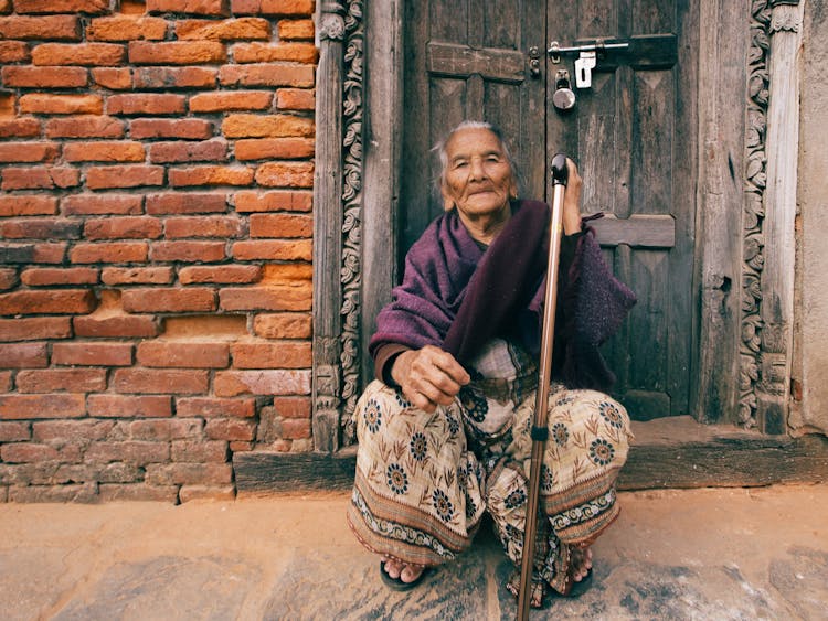 Elderly Woman Crouching With Cane 