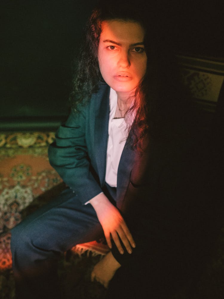 Portrait Of A Woman Wearing Suit Sitting In A Dark Interior