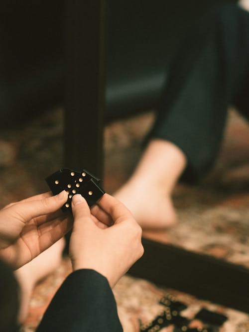 Closeup of People Sitting on a Floor and Playing Domino