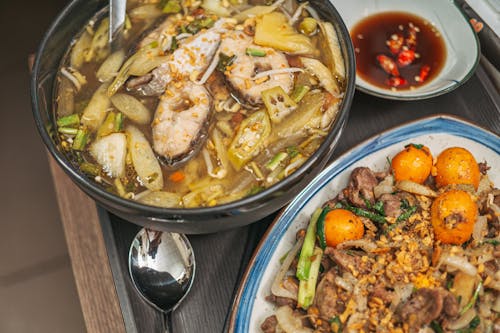 A Soup with Fish Ingredients and a Plate with Meat and Rice on Close-up Photography