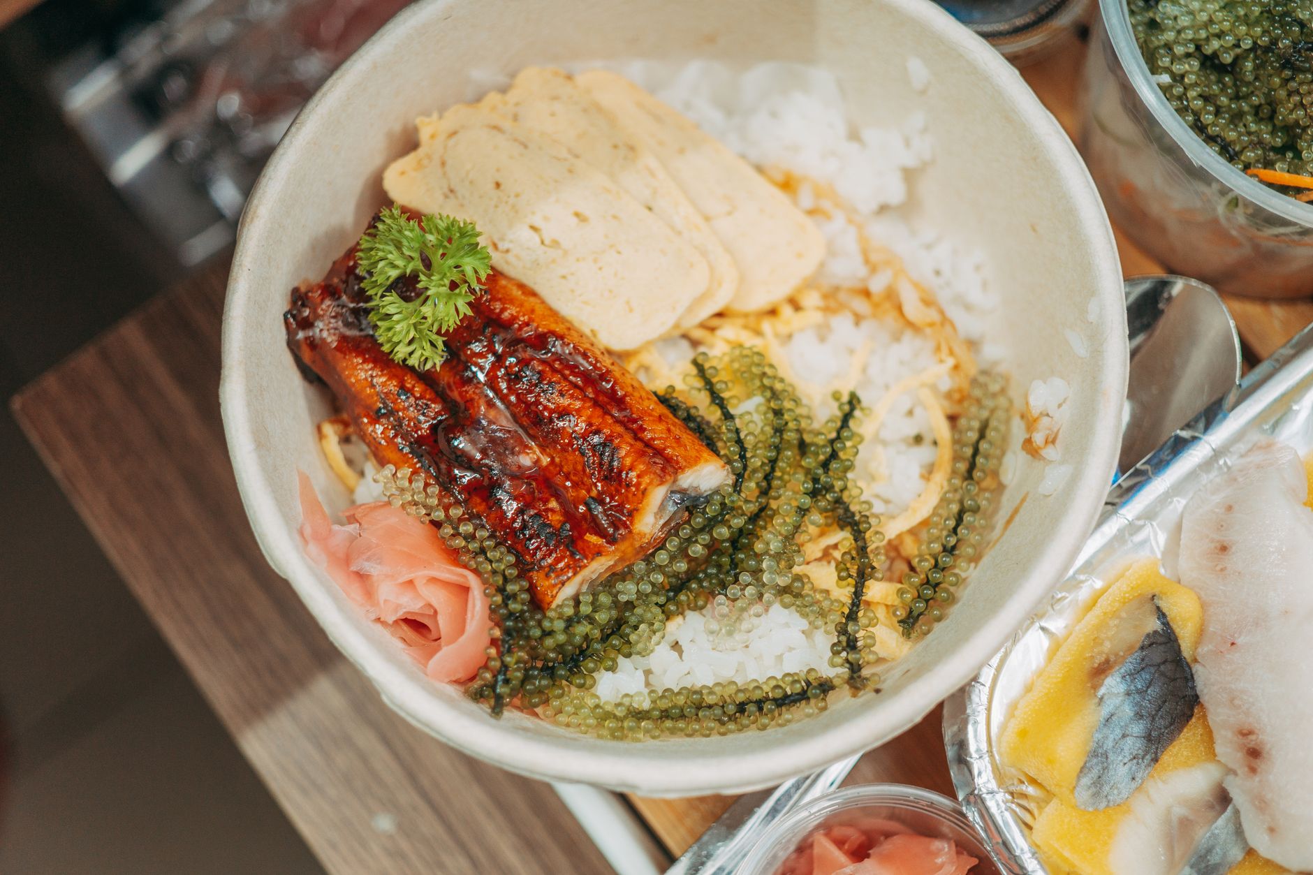 Nahaufnahme einer japanischen Unagi-Reisschale mit Algen, Petersilie und Tamagoyaki, perfekt für die Lebensmittelfotografie.
