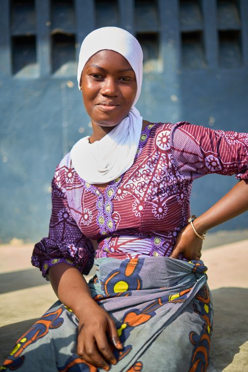Free Portrait of a smiling woman in traditional clothing sitting with hands on waist, Abidjan. Stock Photo