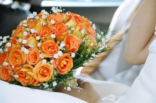 A Person Holding a Bouquet of Beautiful Orange Roses 
